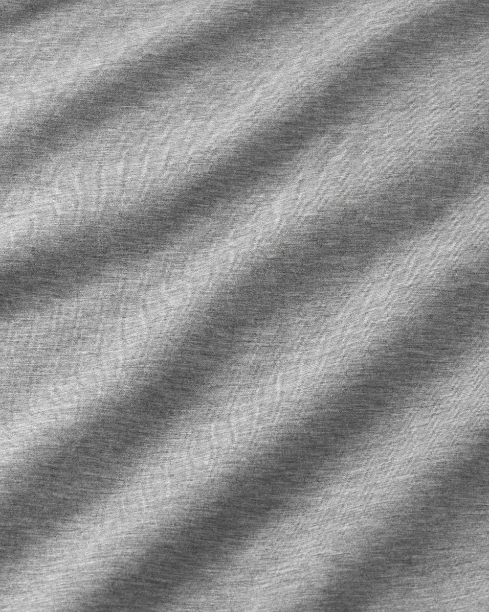 Close-up of a heather gray fabric texture with soft diagonal shadows creating a wavy pattern.