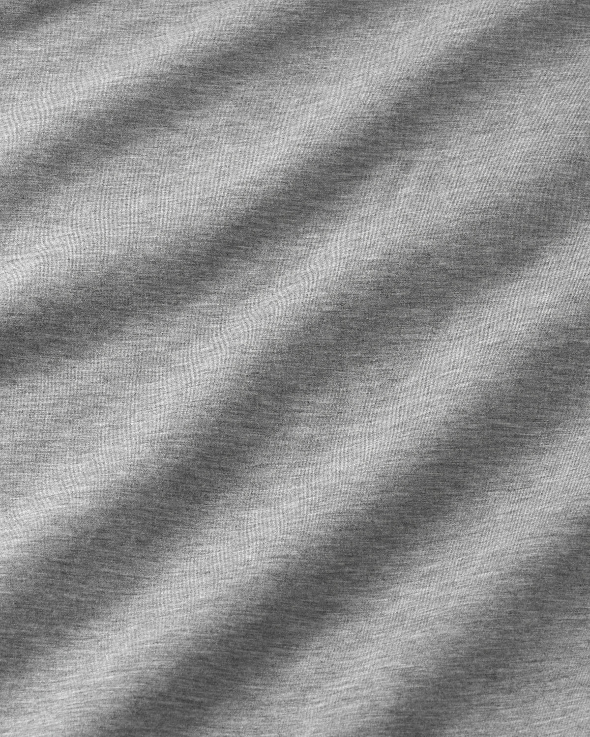 Close-up of a heather gray fabric texture with soft diagonal shadows creating a wavy pattern.