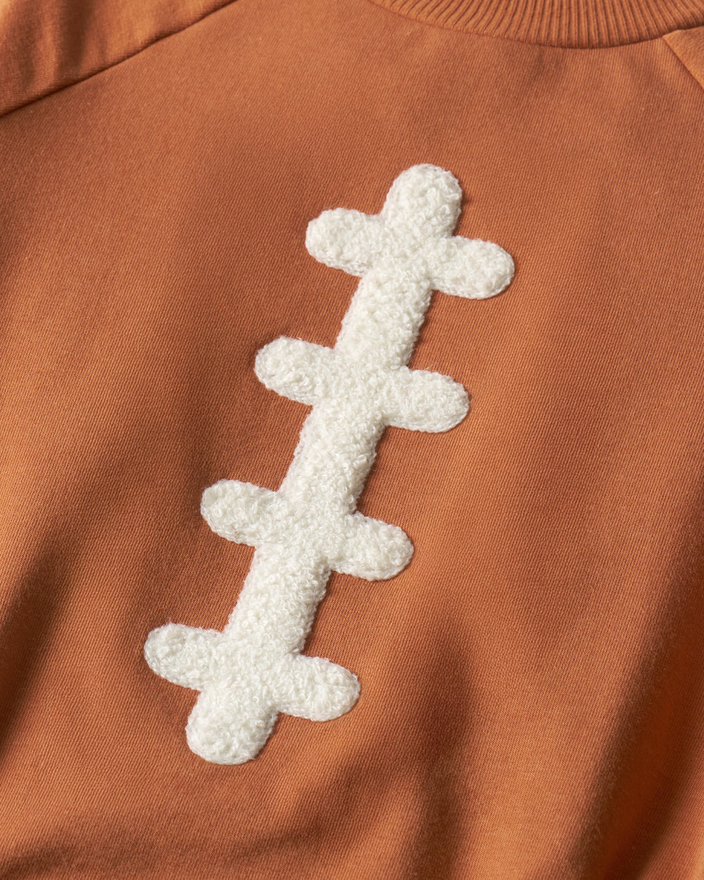 Close up of the Football Raglan Romper embroidery