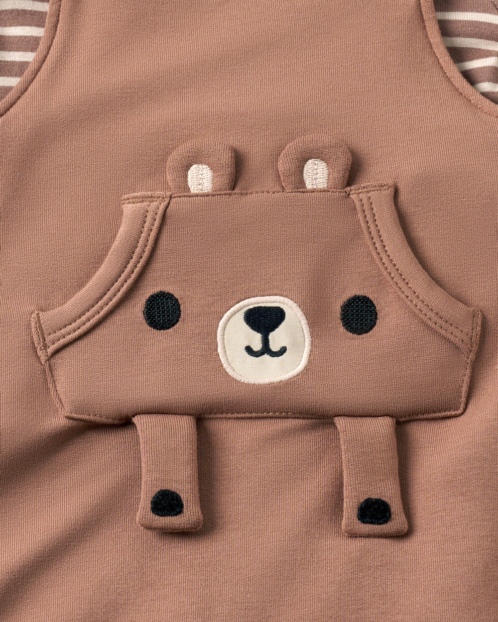 Close-up of a baby tank top in a dusty brown color, featuring an applique bear face design on the front.