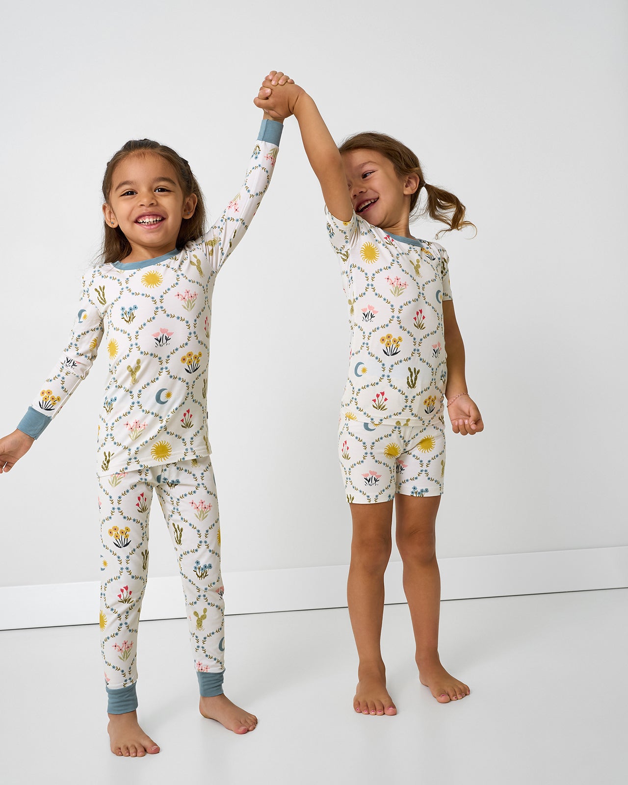 Two girls holding hands wearing matching Desert Meadow Two-Piece Pajama Sets
