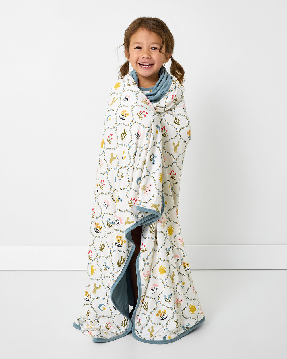 Standing girl wrapped in the Desert Meadow Large Cloud Blanket®