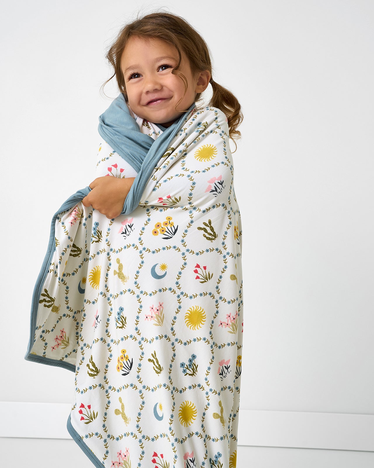 Girl wrapped in the Desert Meadow Large Cloud Blanket®