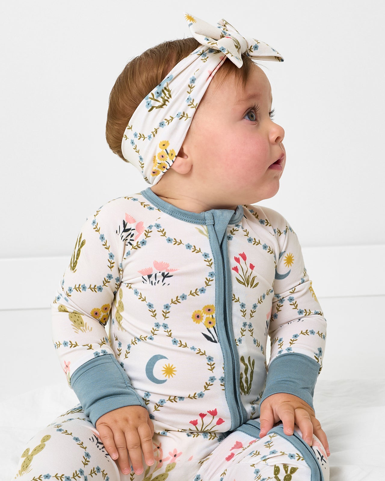 Sitting baby wearing the Desert Meadow Luxe Bow Headband and matching zipper pajamas