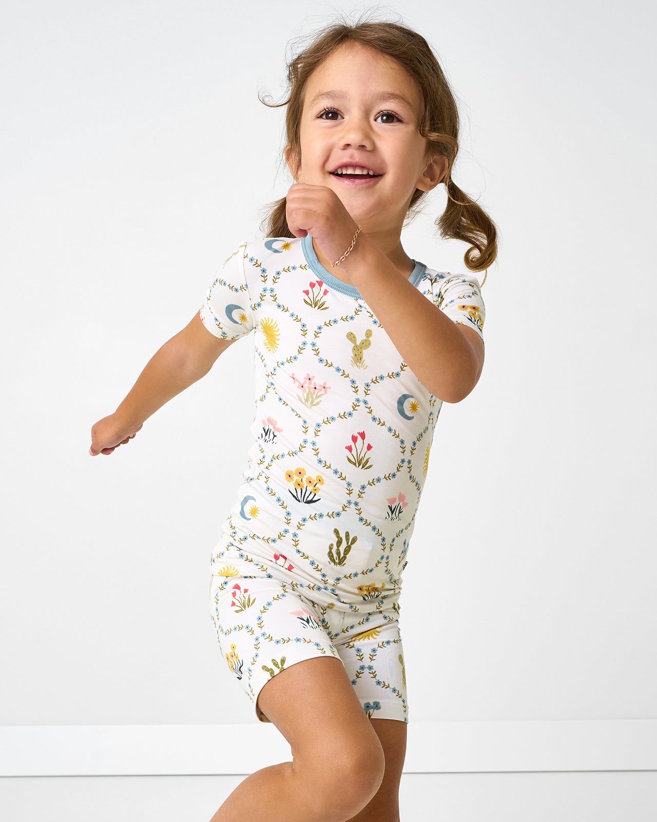 Child in motion wearing the Desert Meadow Two-Piece Short Sleeve & Shorts Pajama Set