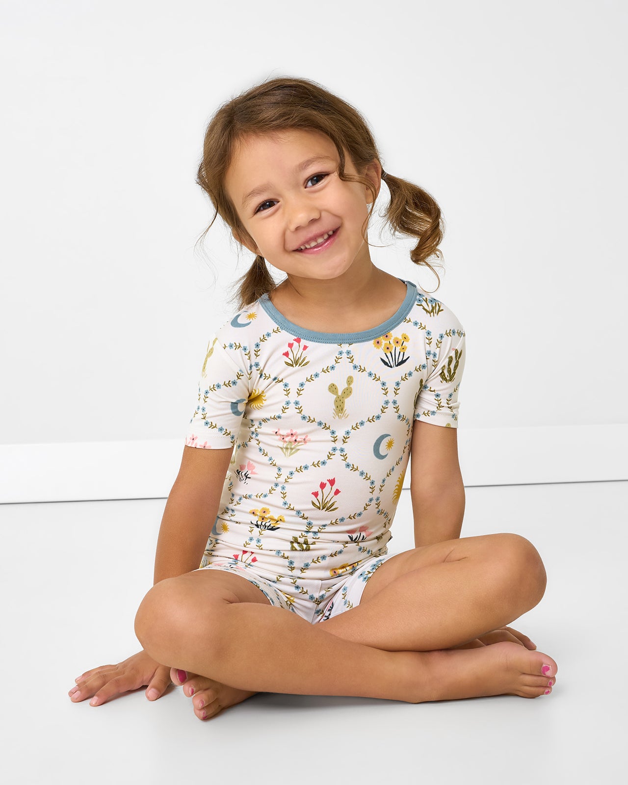 Sitting girl wearing the Desert Meadow Two-Piece Short Sleeve & Shorts Pajama Set