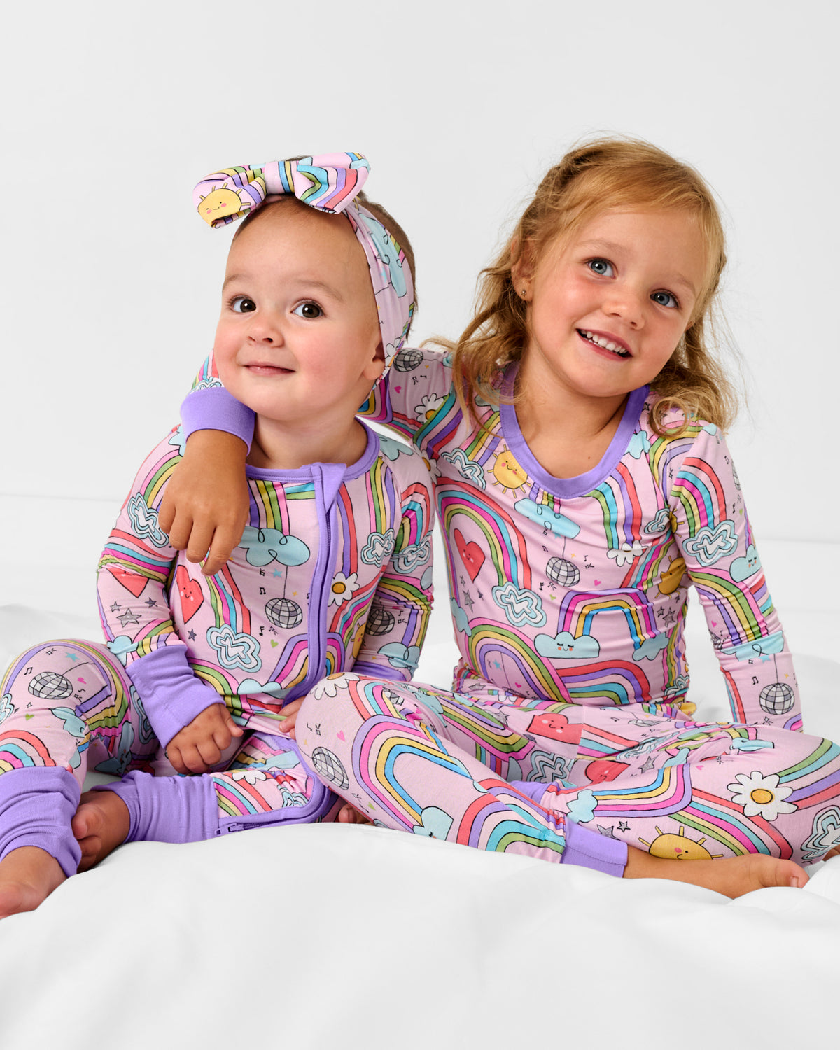 Two children wearing matching Disco Rainbows bamboo pajamas