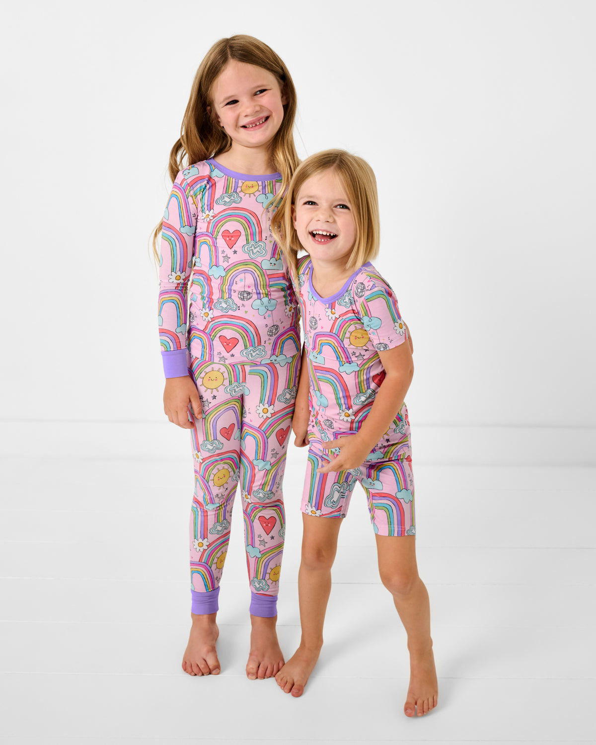 Two girls wearing matching Disco Rainbows Two-Piece Pajama Sets