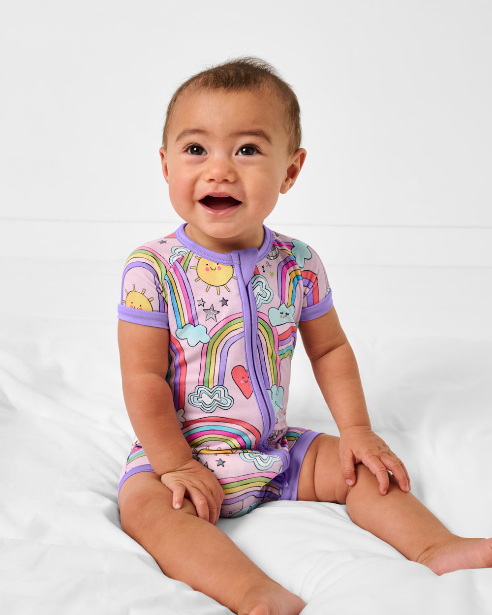 Sitting baby wearing the Disco Rainbows Shorty Zippy