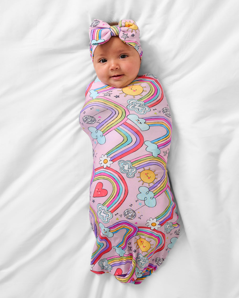 Aerial view of baby wearing the Disco Rainbows Swaddle & Luxe Bow Headband Set
