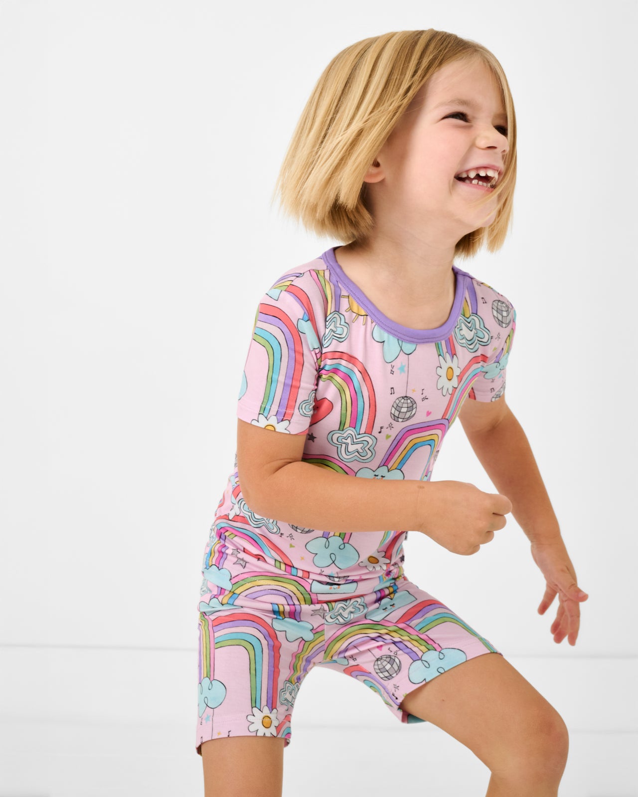Child in motion wearing the Disco Rainbows Two-Piece Short Sleeve & Shorts Pajama Set