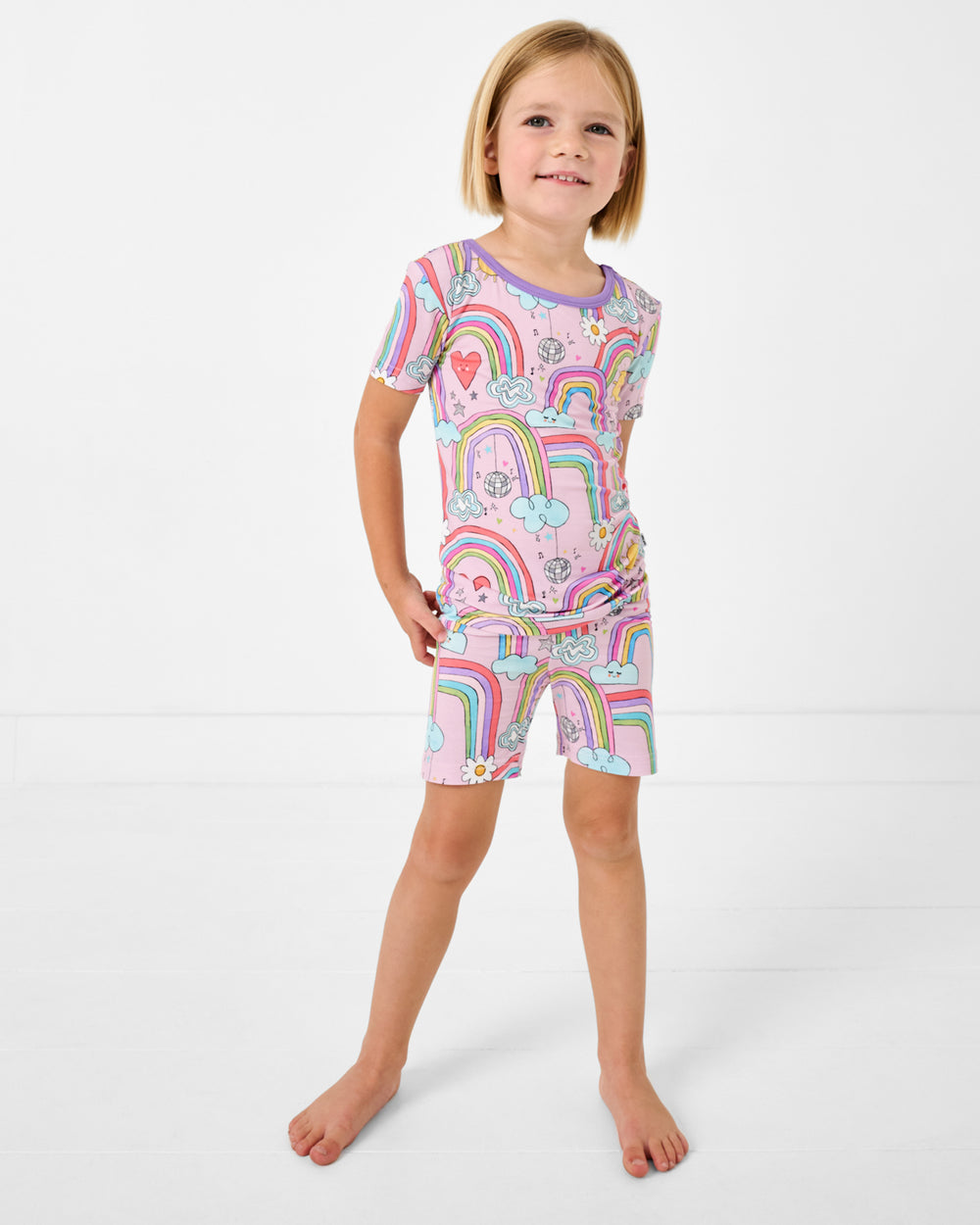 Standing girl wearing the Disco Rainbows Two-Piece Short Sleeve & Shorts Pajama Set