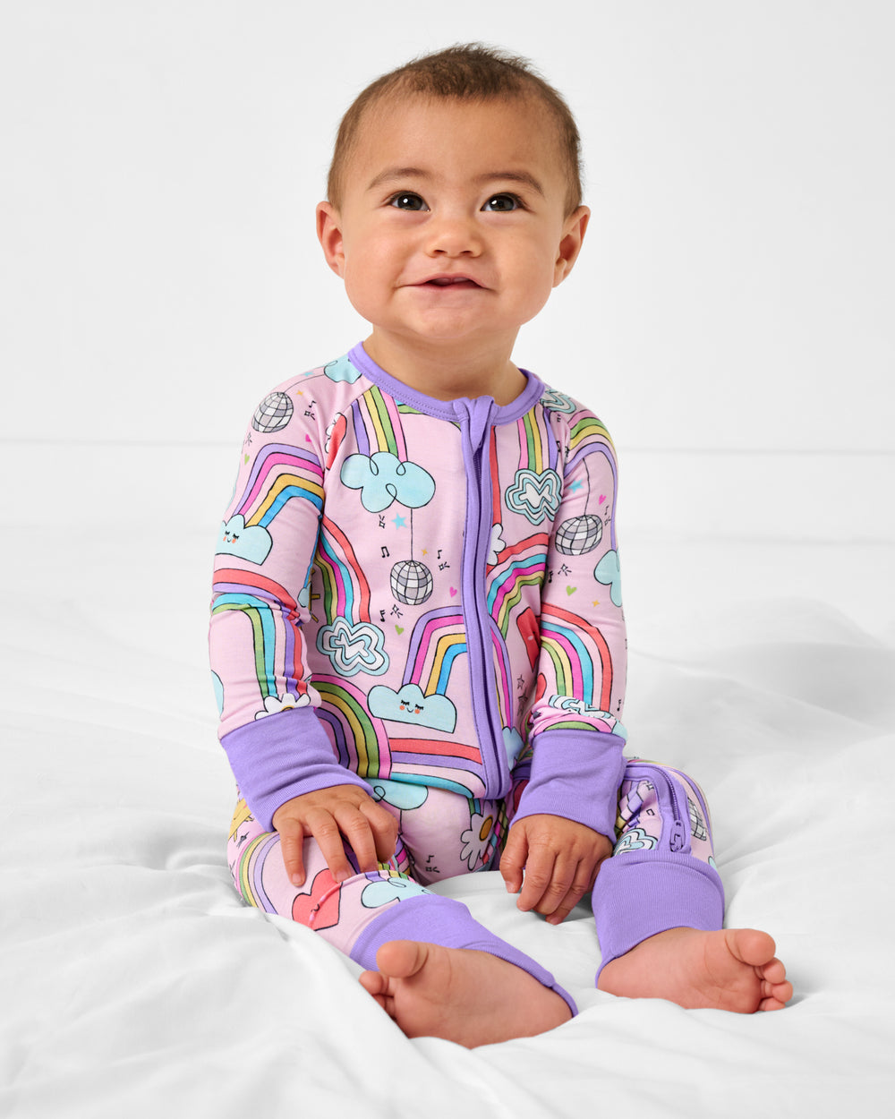 Sitting baby wearing the Disco Rainbows Zippy