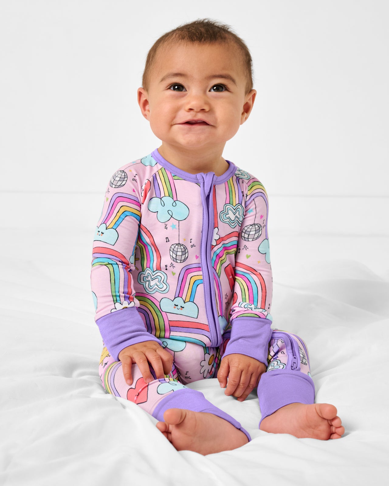 Sitting baby wearing the Disco Rainbows Zippy