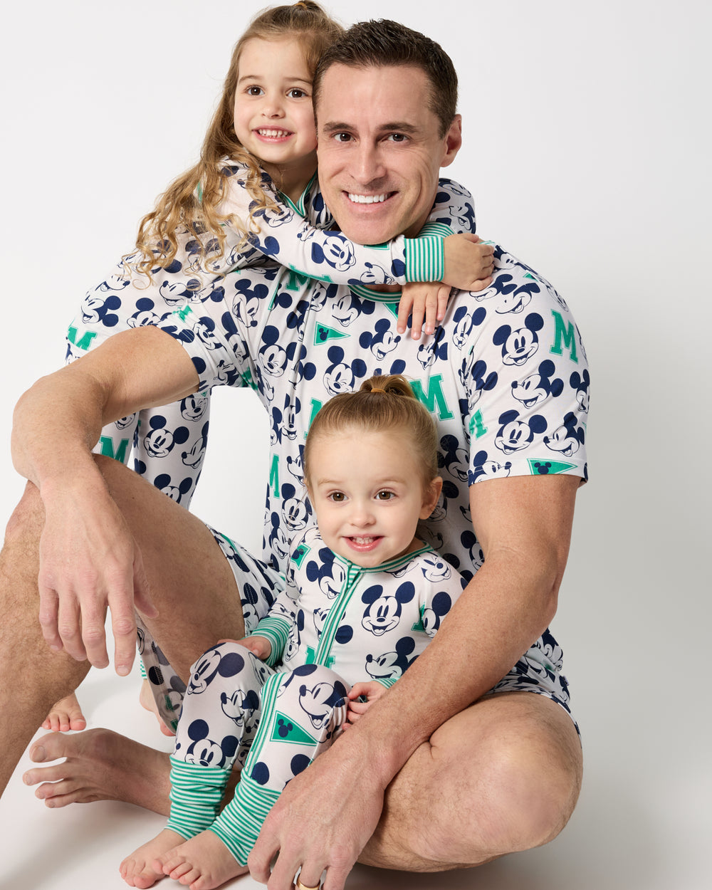 Father and two kids wearing matching Disney Varsity Mickey Mouse print shorts