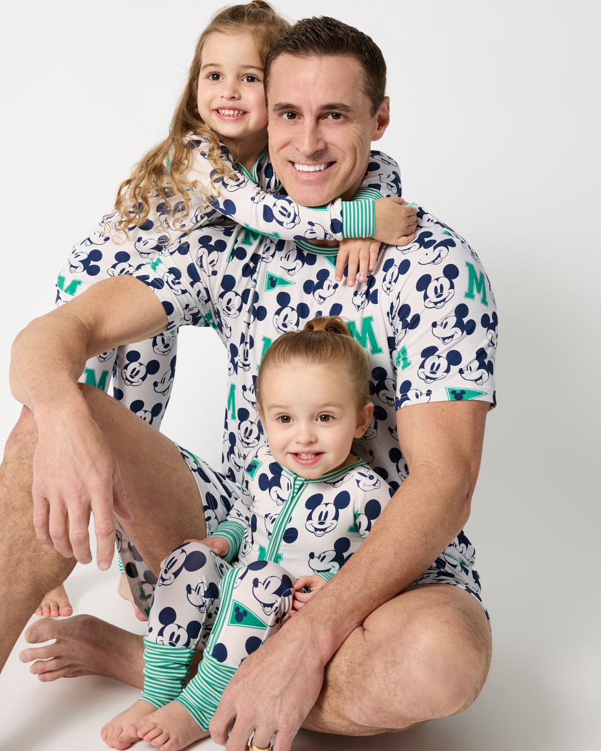 Father and two kids wearing matching Disney Varsity Mickey Mouse print shorts