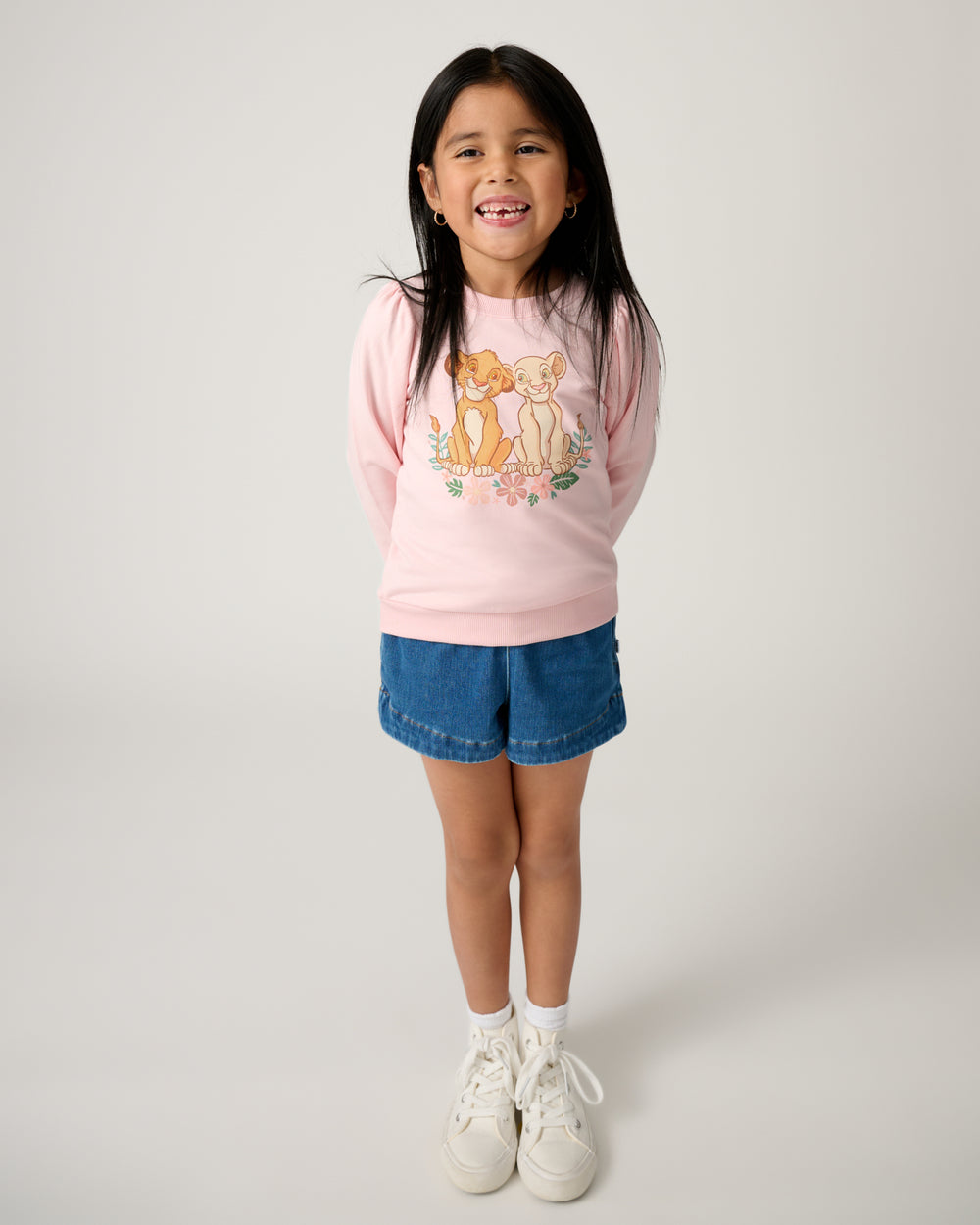 Girl wearing the Disney Cub Club Puff Sleeve Crewneck with denim shorts