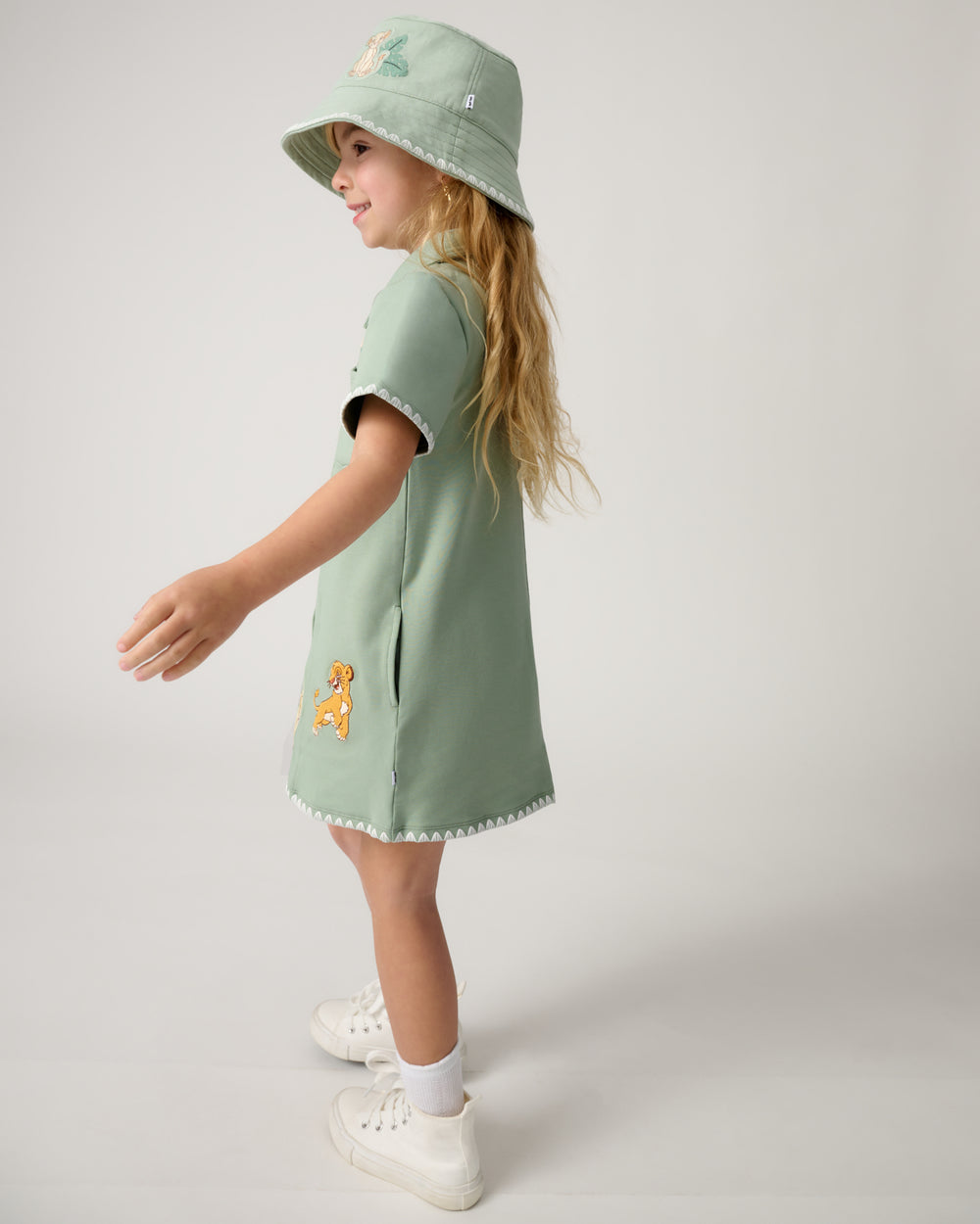 Side view of girl wearing the Disney Cub Club Button Dress and bucket hat