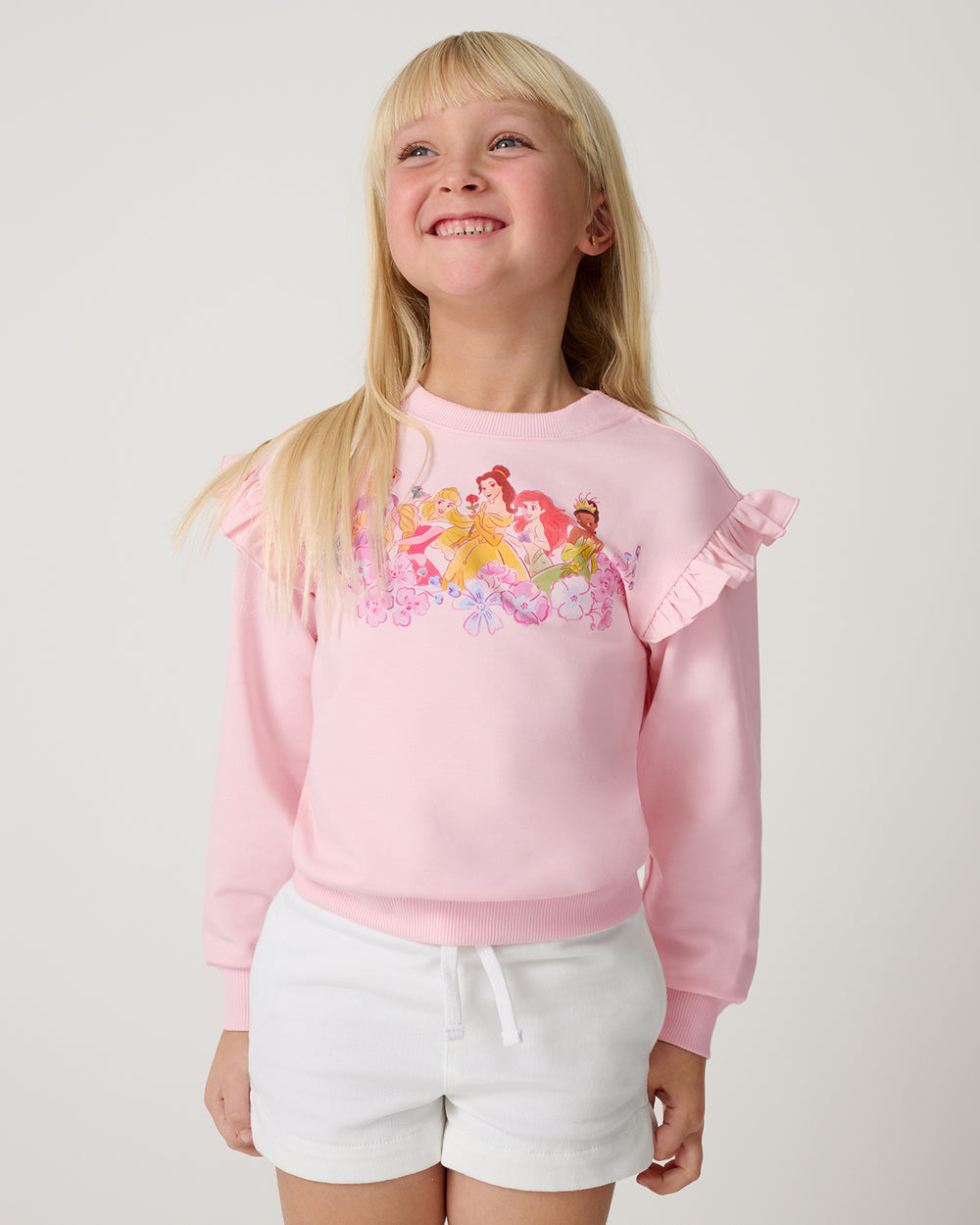 Close up of girl wearing the Disney Floral Fairytale Flutter Crewneck with white denim shorts