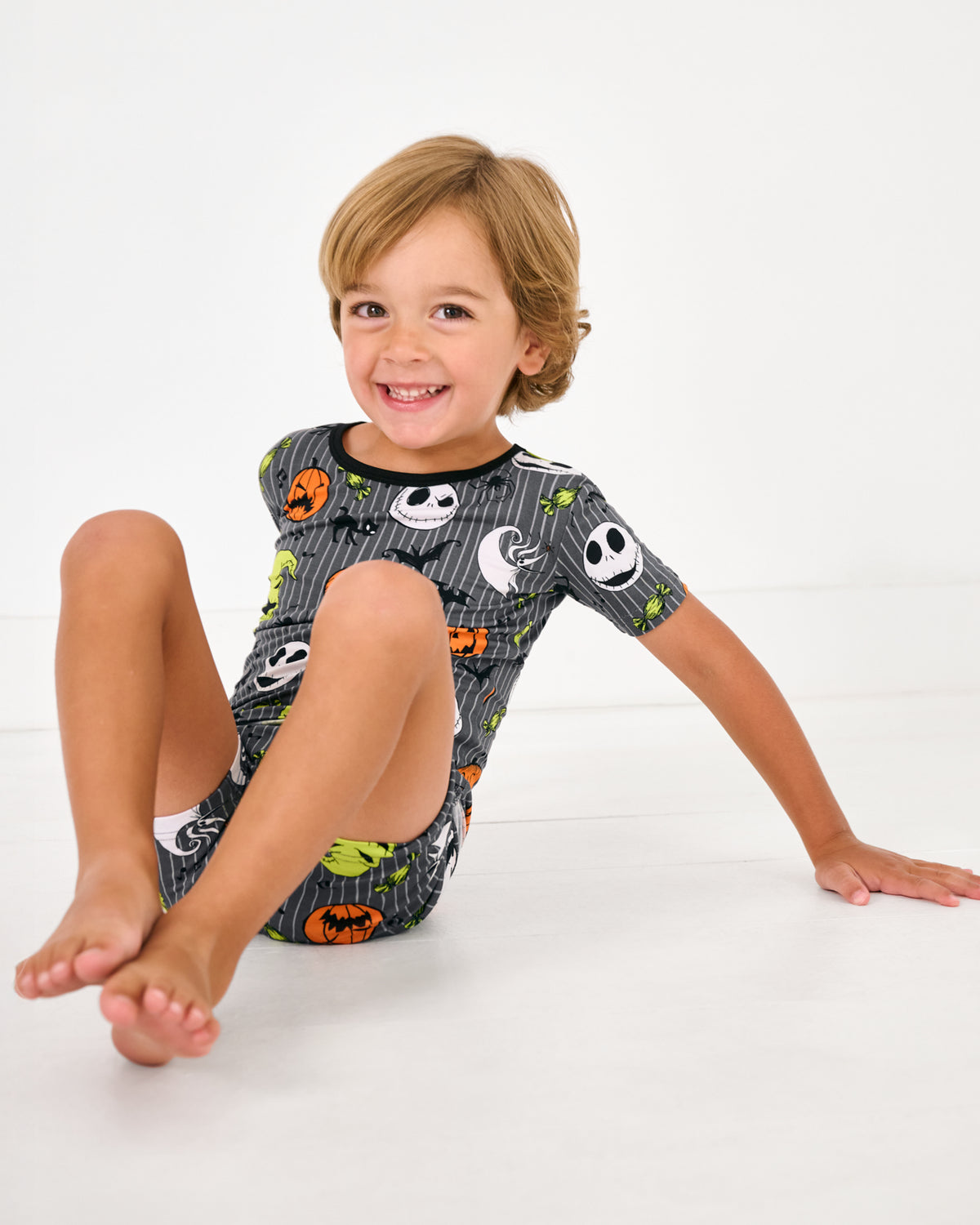 Sitting boy wearing the Disney The Nightmare Before Christmas Two-Piece Short Sleeve & Shorts Pajama Set