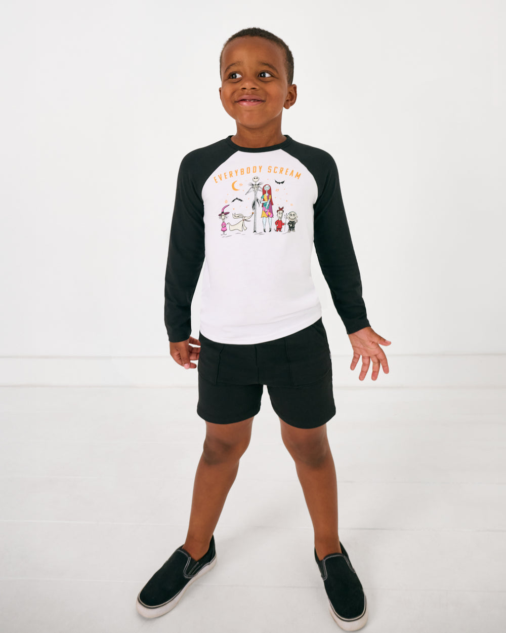 Standing boy wearing the Disney Everybody Scream Raglan Tee with black shorts