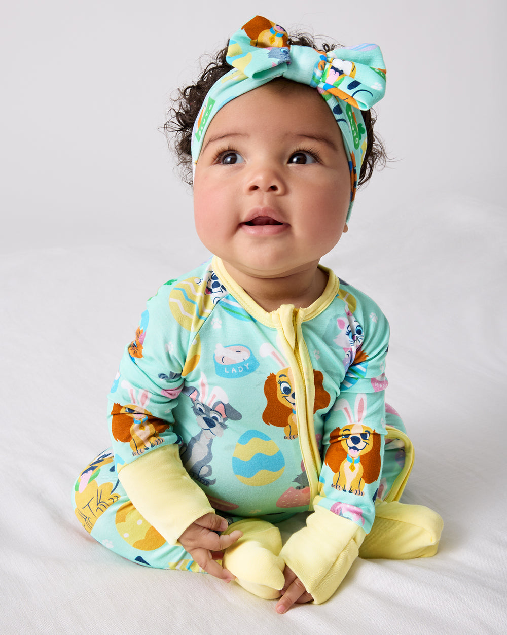 Sitting baby wearing the Disney Peekaboo Pets Luxe Bow Headband