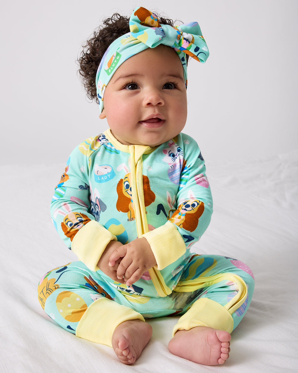 Sitting baby wearing the Disney Peekaboo Pets Zippy and Luxe Bow