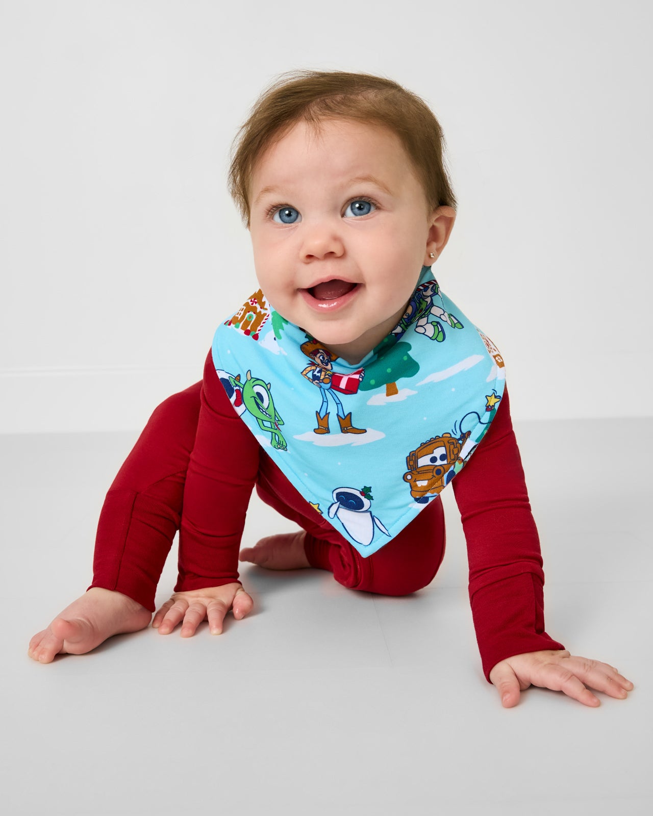 Crawling baby wearing the Disney & Pixar Christmas Village Bandana Bib
