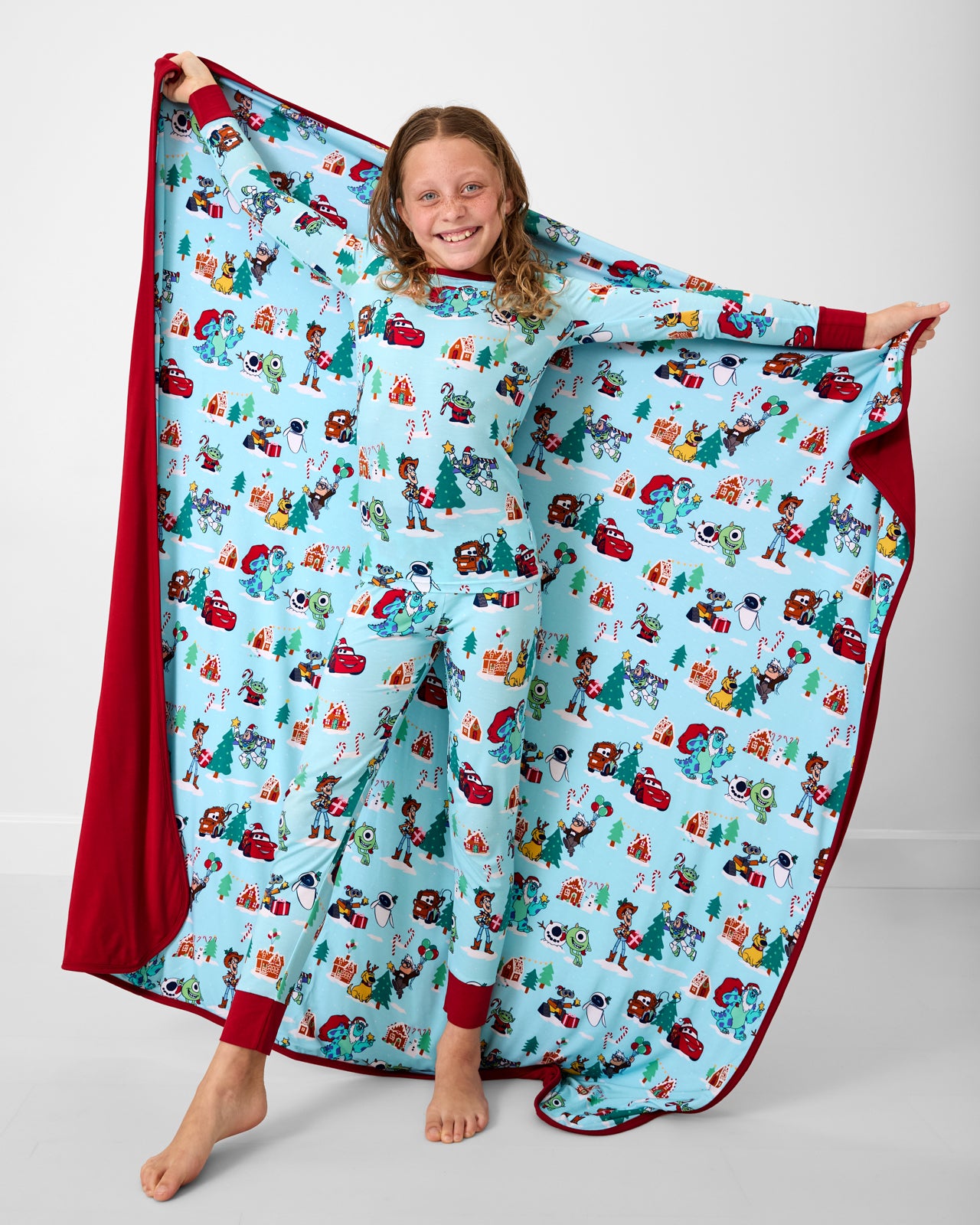 Girl holding up the Disney & Pixar Christmas Village Large Cloud Blanket®