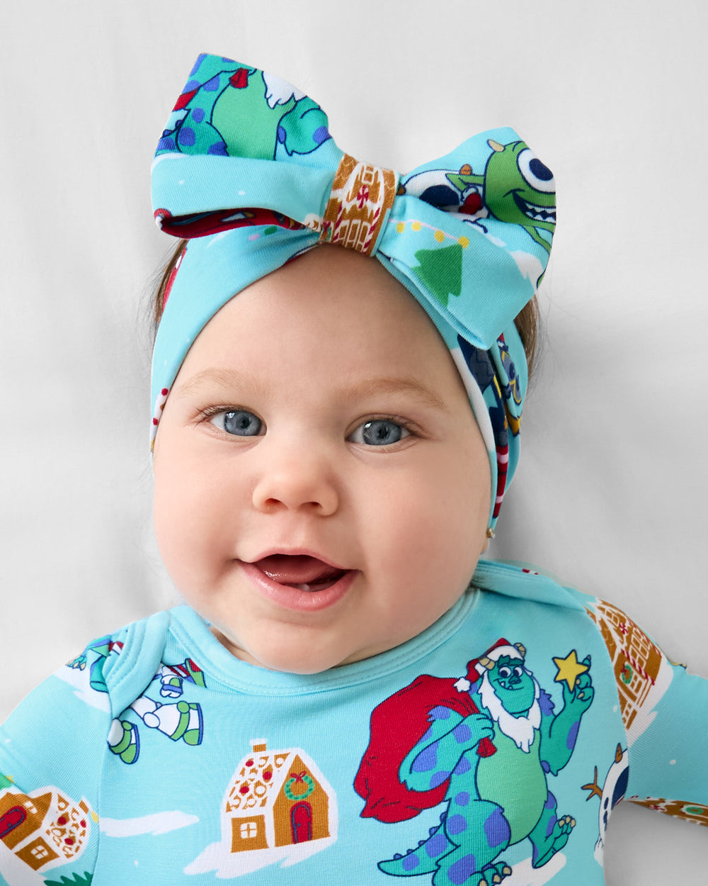 Close up of baby wearing the Disney & Pixar Christmas Village Luxe Bow Headband