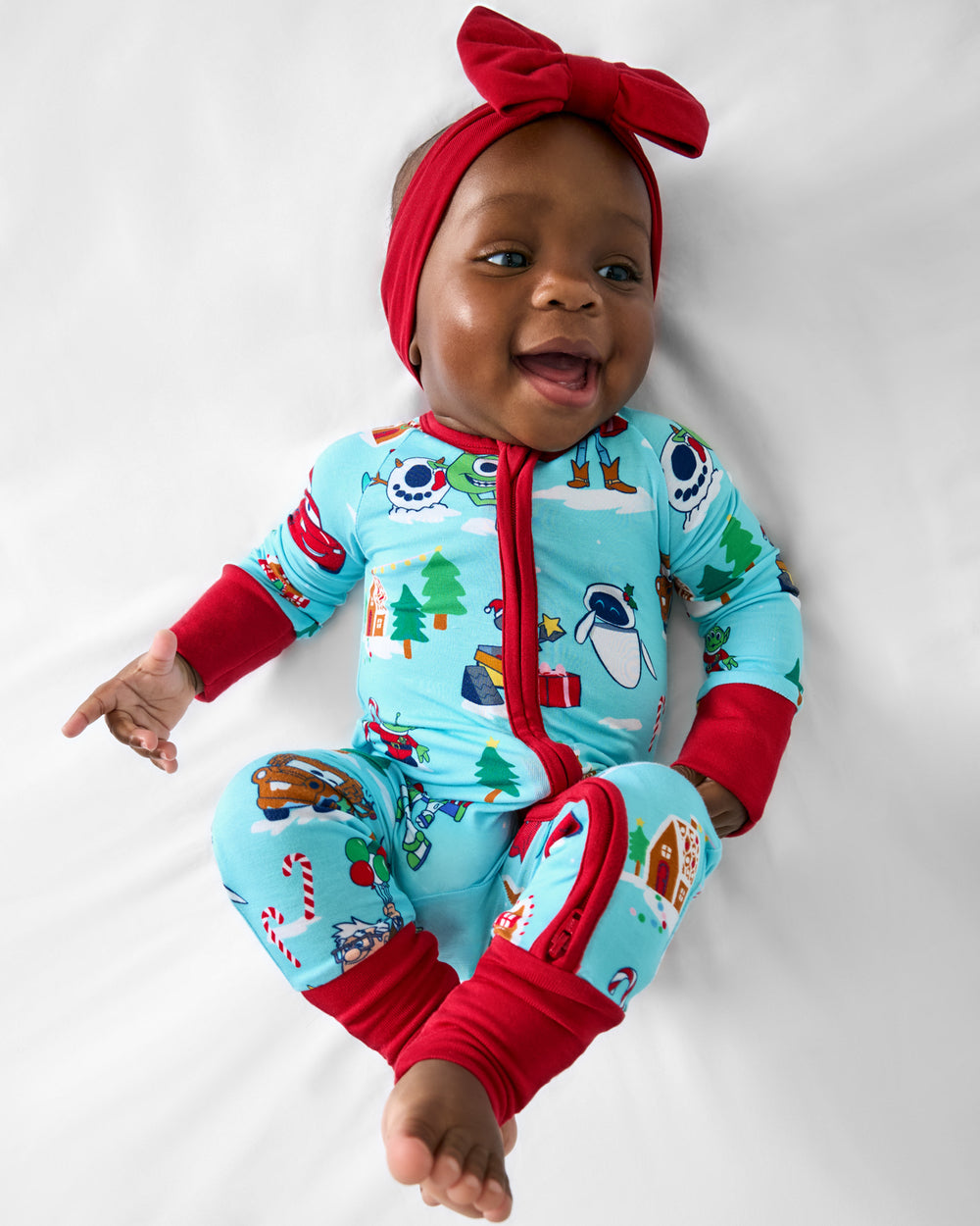 Aerial view of baby wearing the Disney & Pixar Christmas Village Zippy with a holiday red luxe bow headband