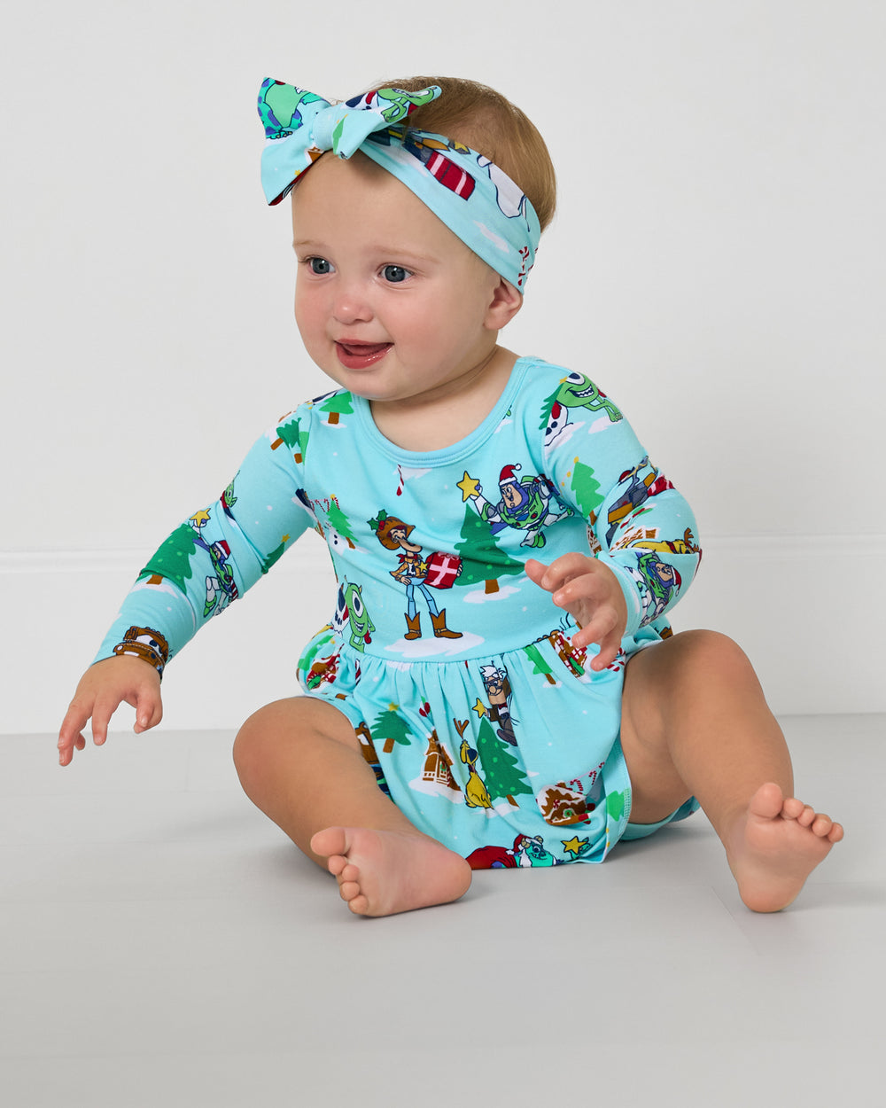 Sitting baby wearing the Disney & Pixar Christmas Village Skater Dress with Bodysuit