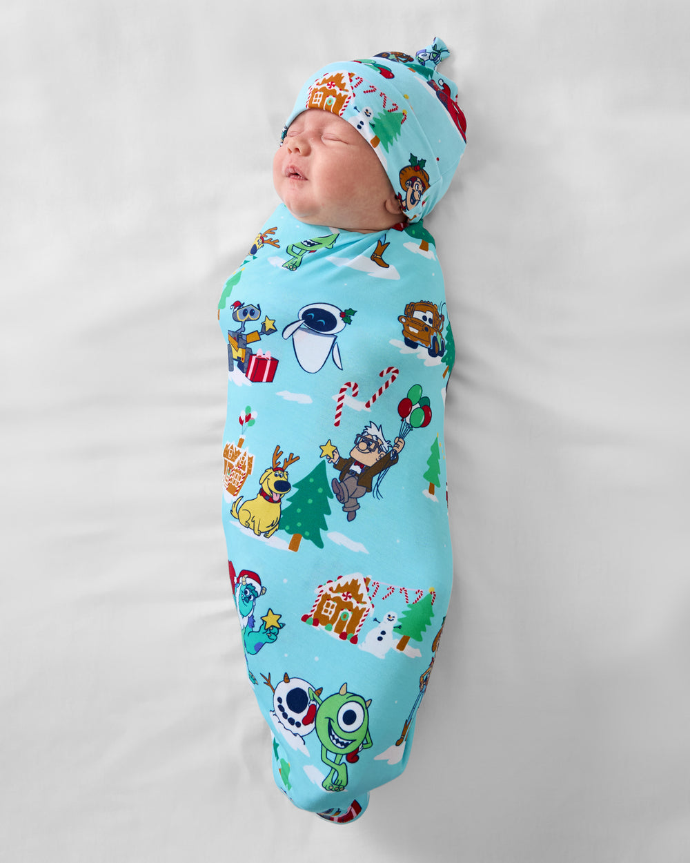 Aerial view of baby wearing the Disney & Pixar Christmas Village Swaddle & Hat Set