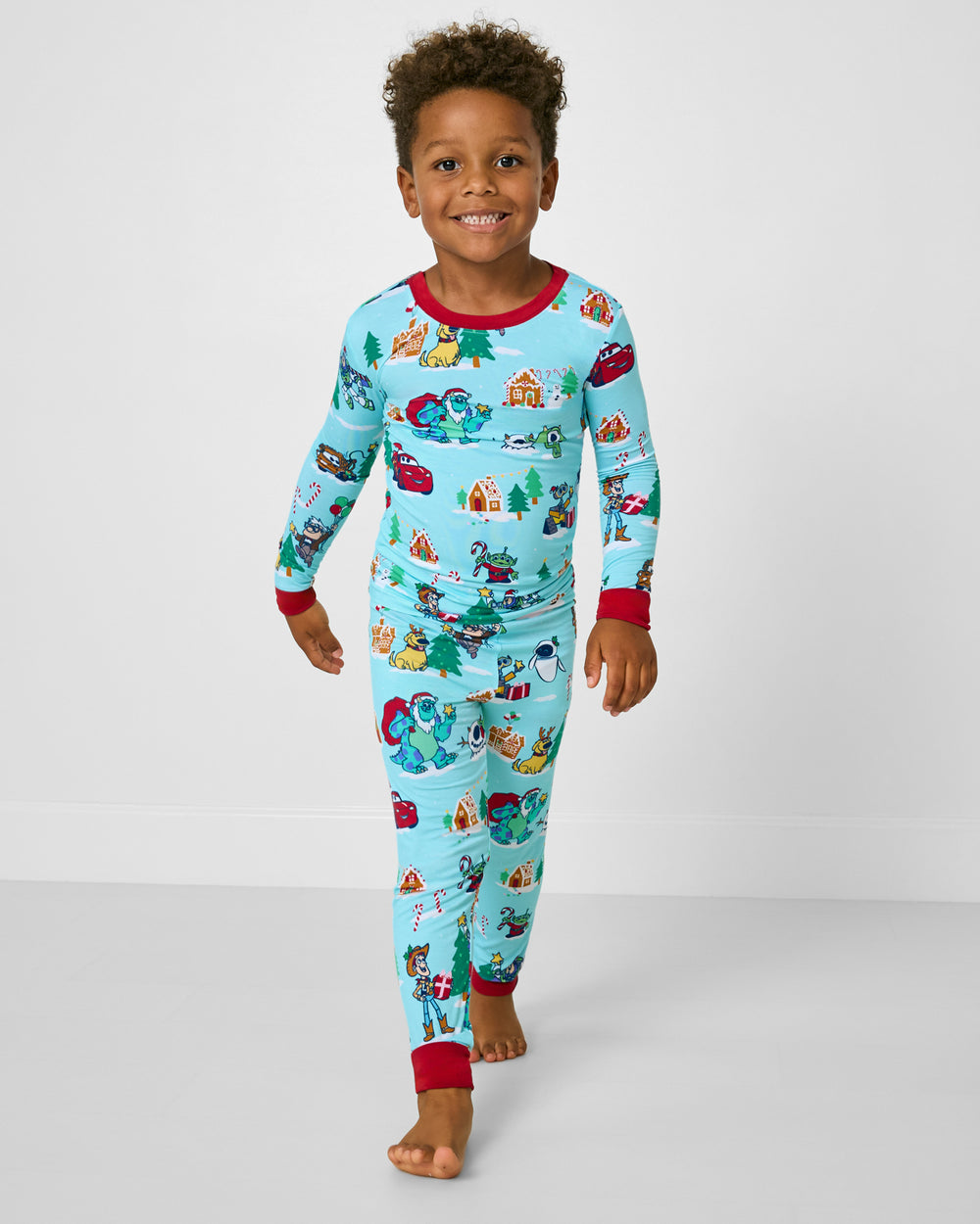 Walking boy wearing the Disney & Pixar Christmas Village Two-Piece Pajama Set