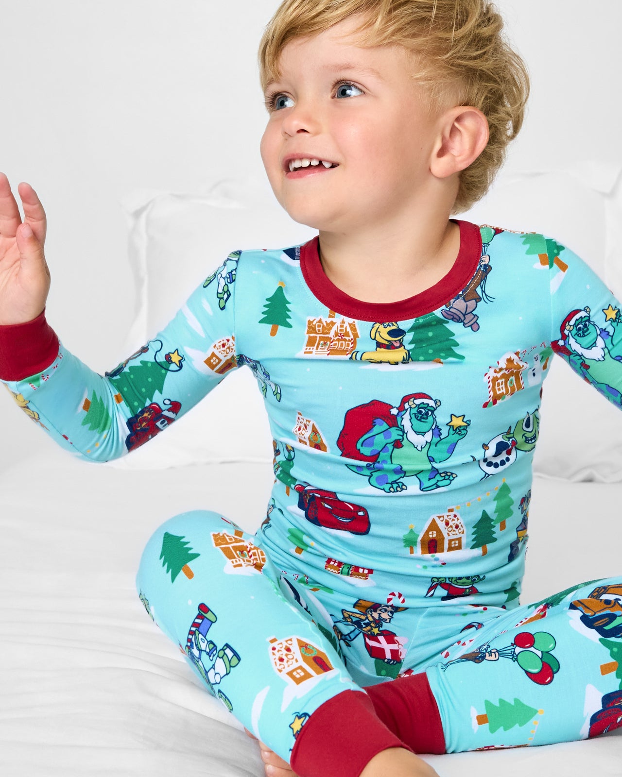 Sitting boy wearing the Disney & Pixar Christmas Village Two-Piece Pajama Set