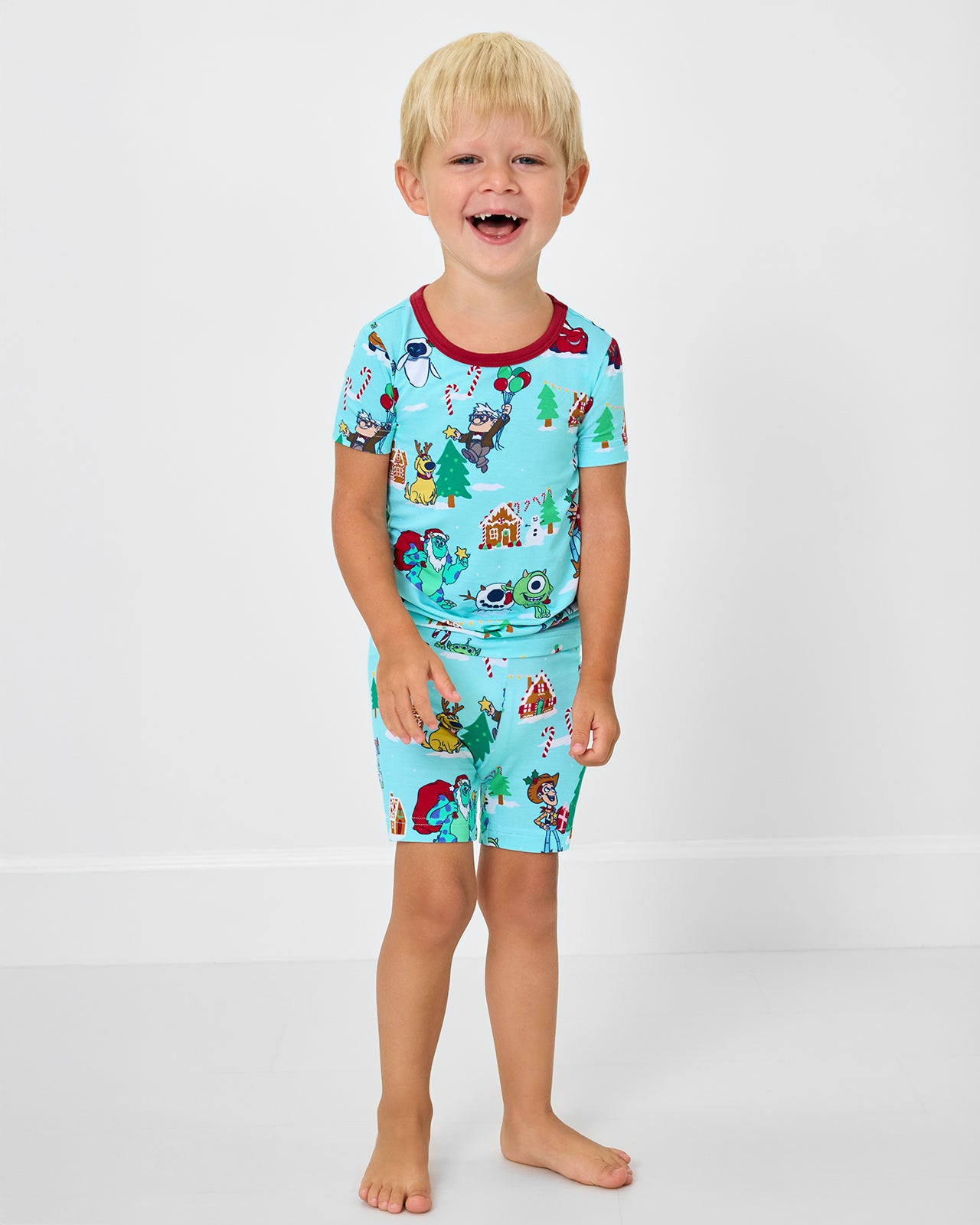 Boy wearing the Disney & Pixar Christmas Village Two-Piece Short Sleeve & Shorts Pajama Set