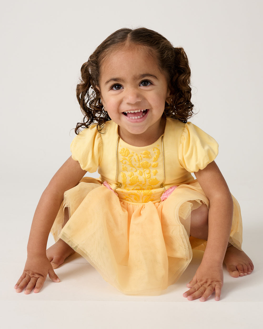 Crouching toddler wearing the Disney Princess Belle Dress with Bodysuit