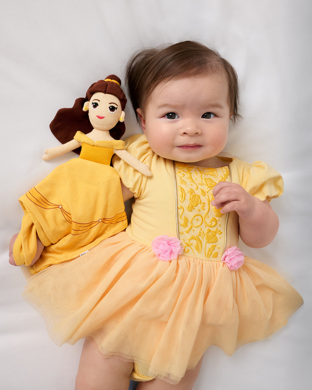 Aerial view of baby wearing the Disney Princess Belle Dress with Bodysuit and holding the Belle Lovey
