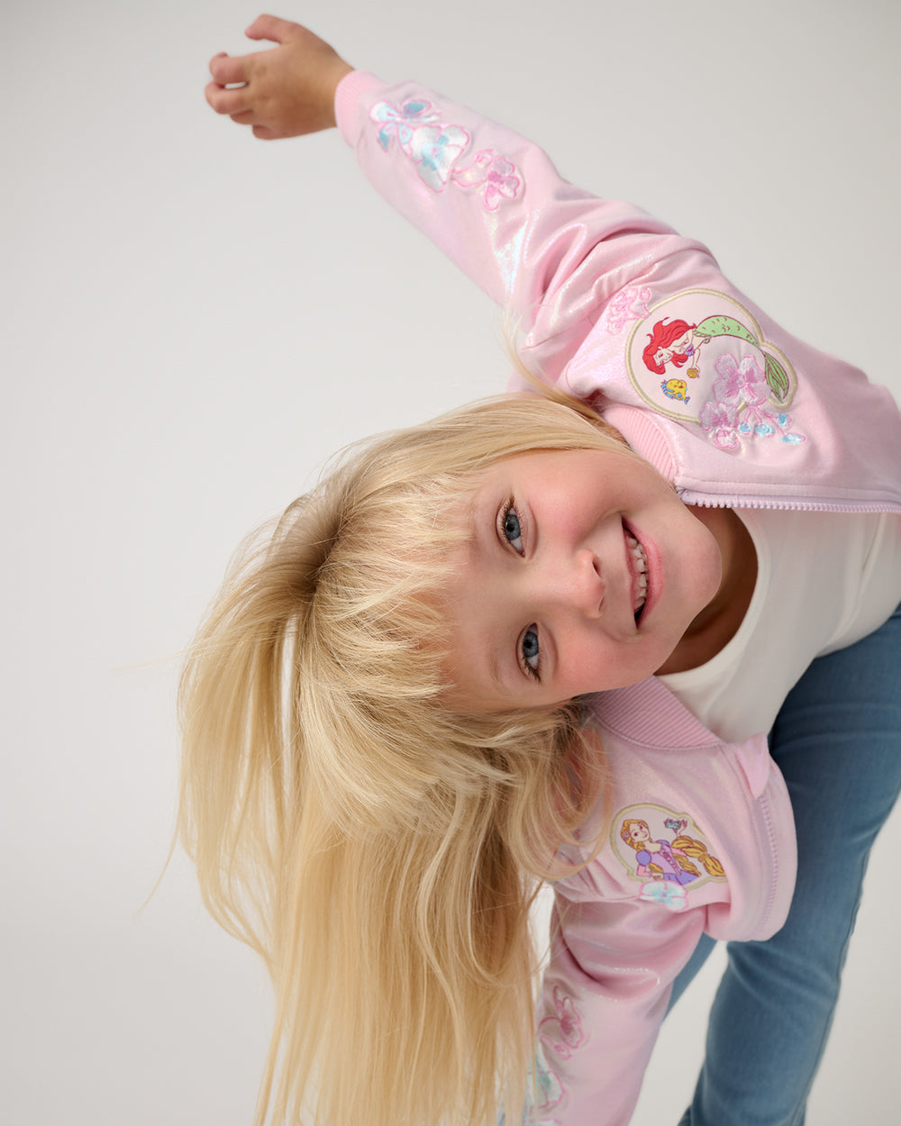 Posing girl wearing the Disney Princess Iridescent Varsity Jacket