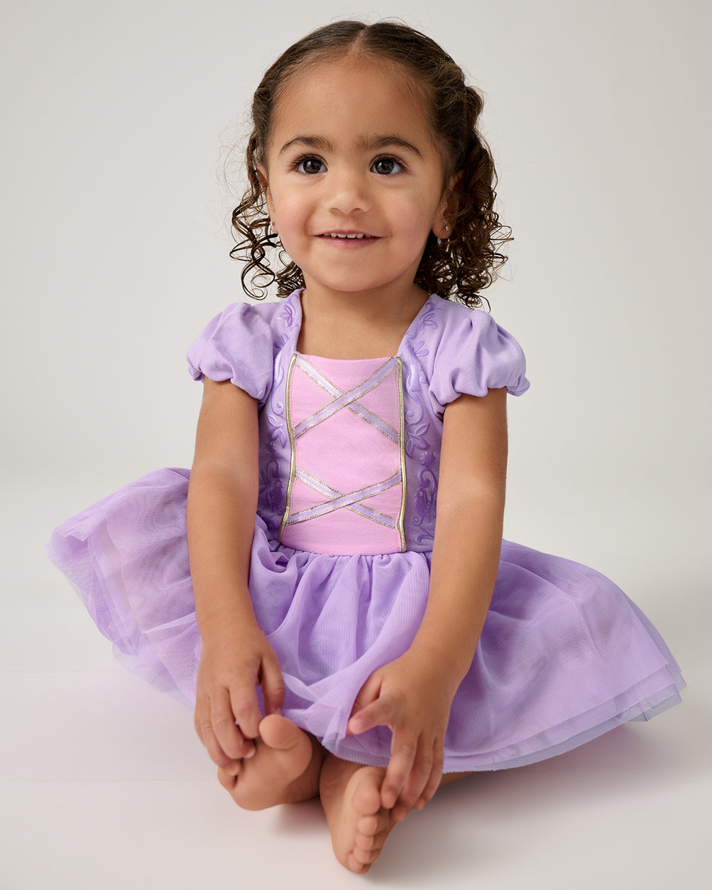 Sitting toddler wearing the Disney Princess Rapunzel Dress with Bodysuit