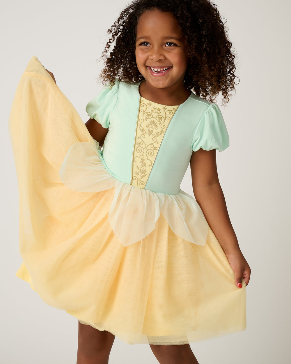 Girl wearing the Disney Princess Tiana Dress holding up the tulle skirt
