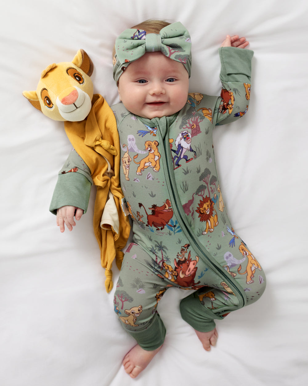Aerial view of baby wearing the Disney Simba's Safari Zippy laying with a Simba Lovey