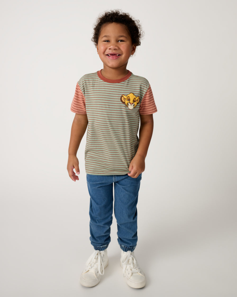 Boy wearing the Disney Simba Stripe Relaxed Tee with denim joggers