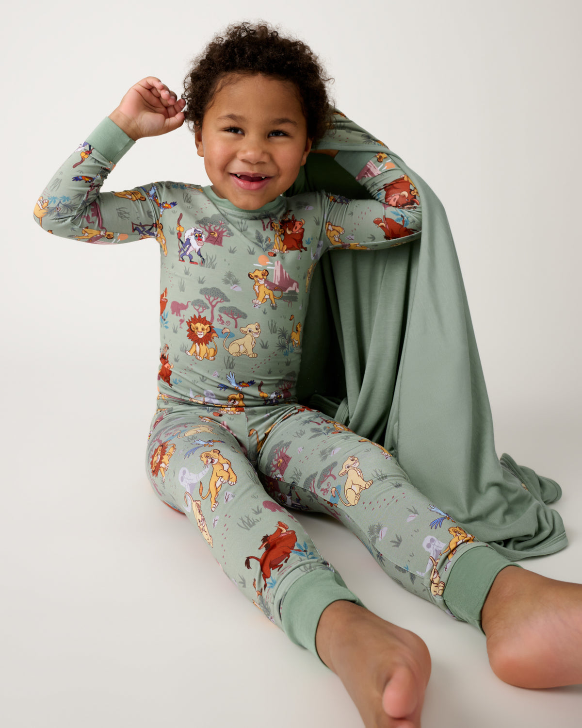 Sitting child holding the Disney Simba's Safari Large Cloud Blanket®