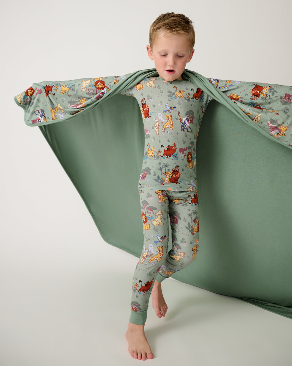 Child holding up the Disney Simba's Safari Large Cloud Blanket® showing the solid green side