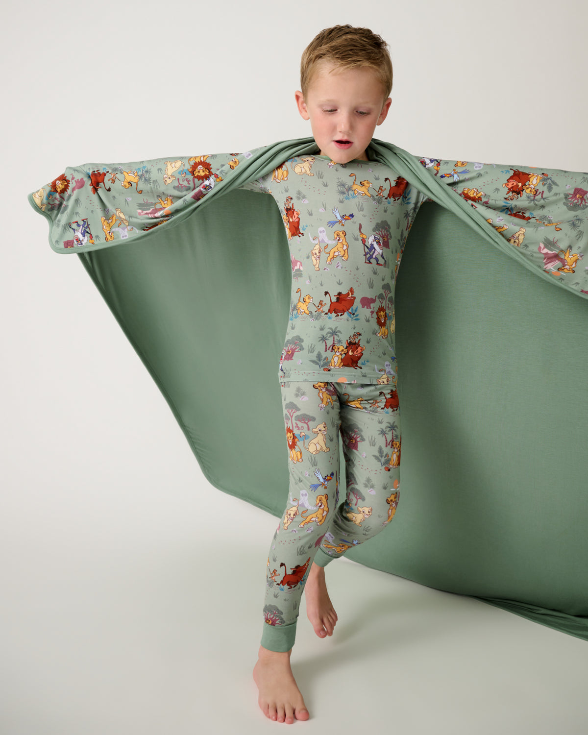 Child holding up the Disney Simba's Safari Large Cloud Blanket® showing the solid green side