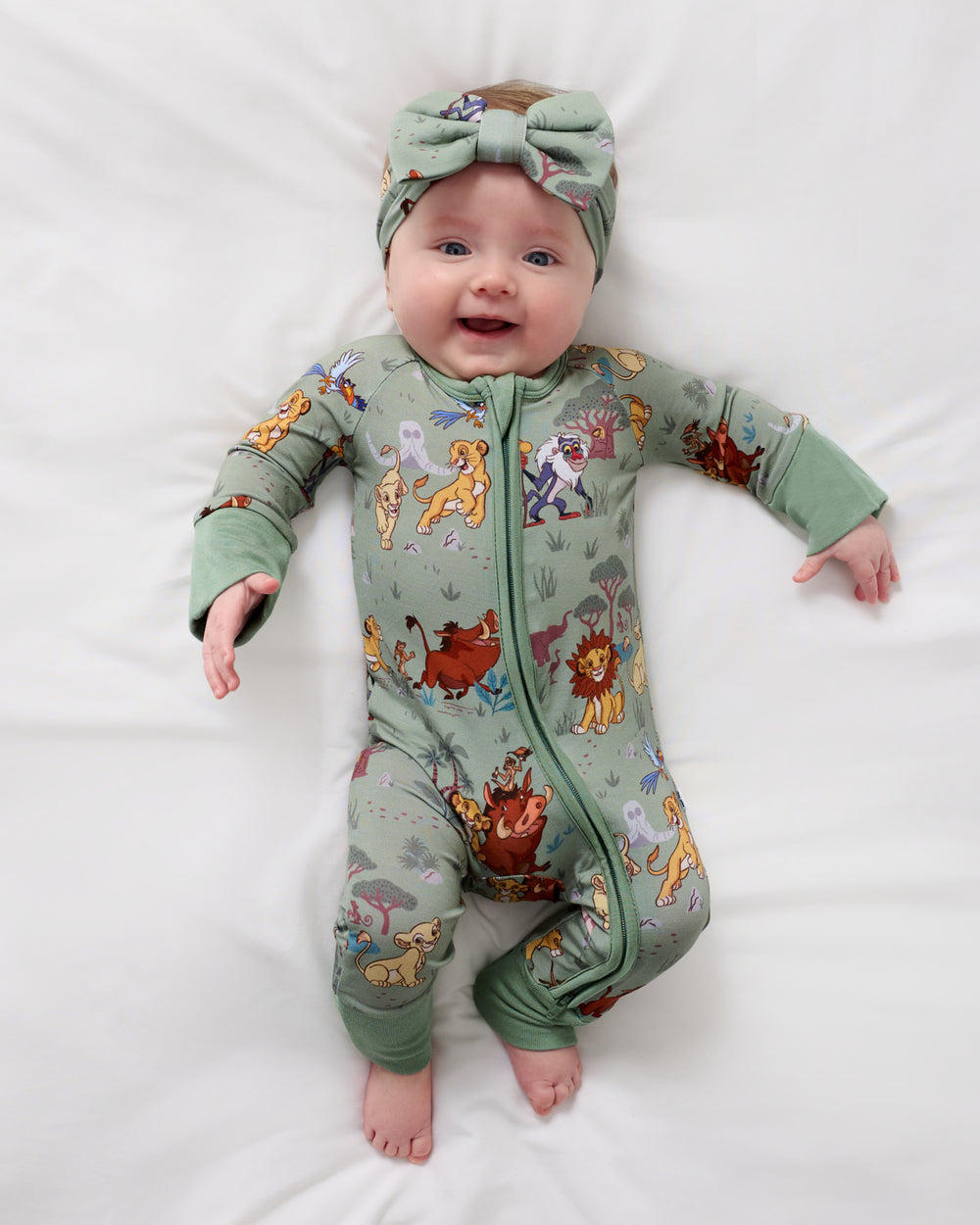 Aerial view of baby wearing the Disney Simba's Safari Luxe Bow Headband and Zipper Pajamas