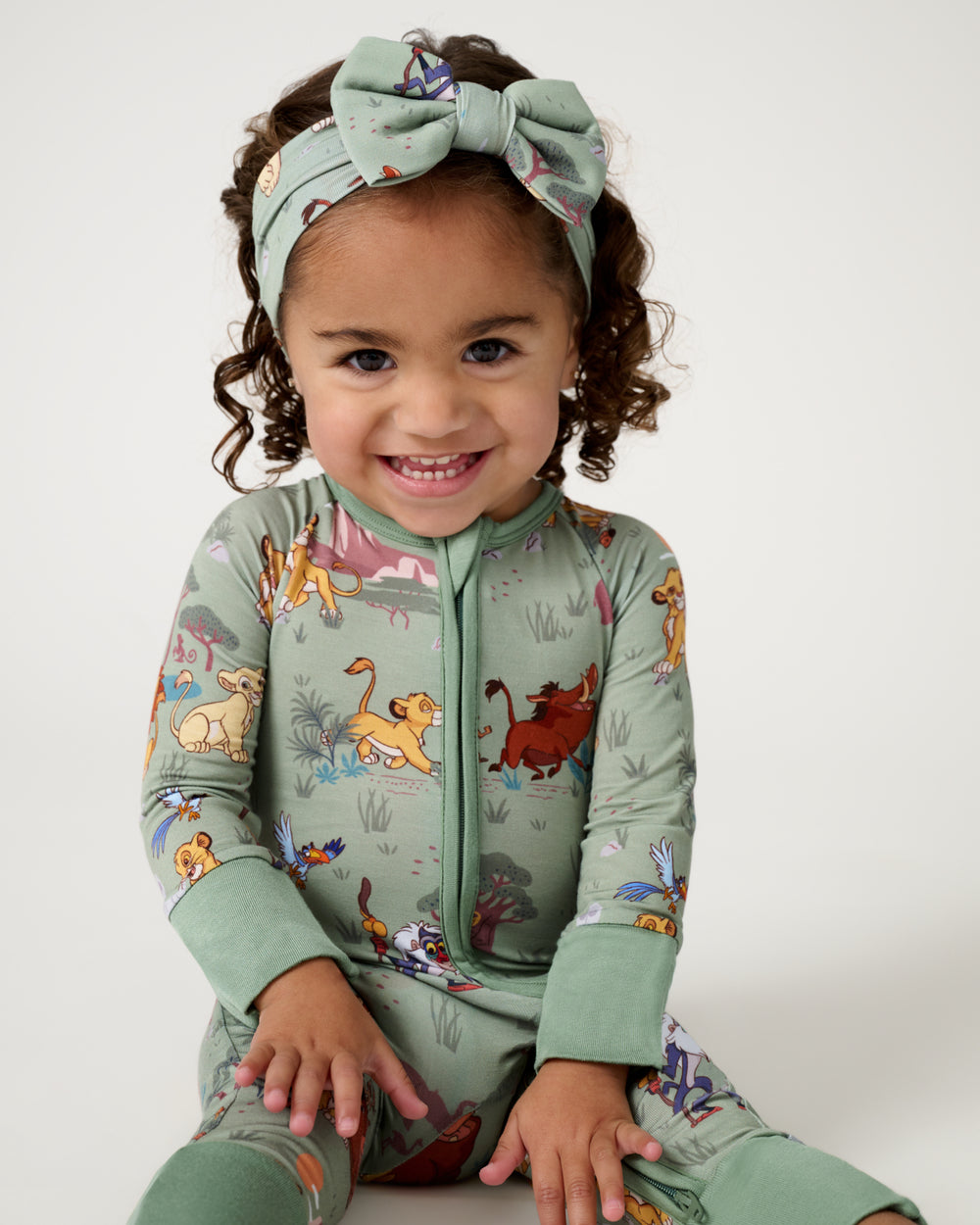 Sitting toddler wearing the Disney Simba's Safari Zippy and Bow Headband