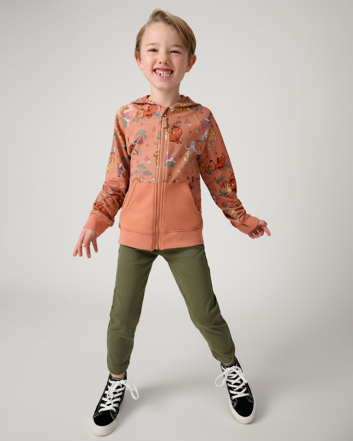 Standing boy wearing the Disney Simba's Safari Zip Hoodie with green jpggers