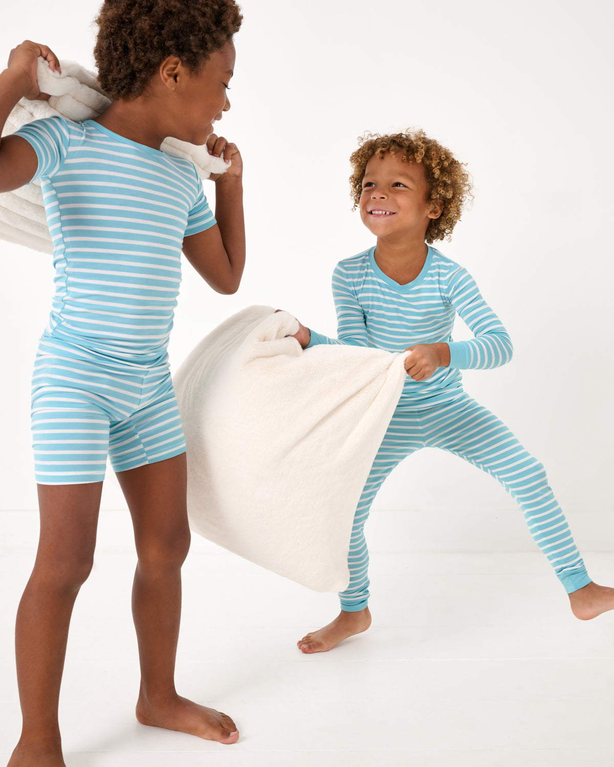 Two boys having a pillow fight wearing matching Dockside Stripe Two-Piece Pajama Sets